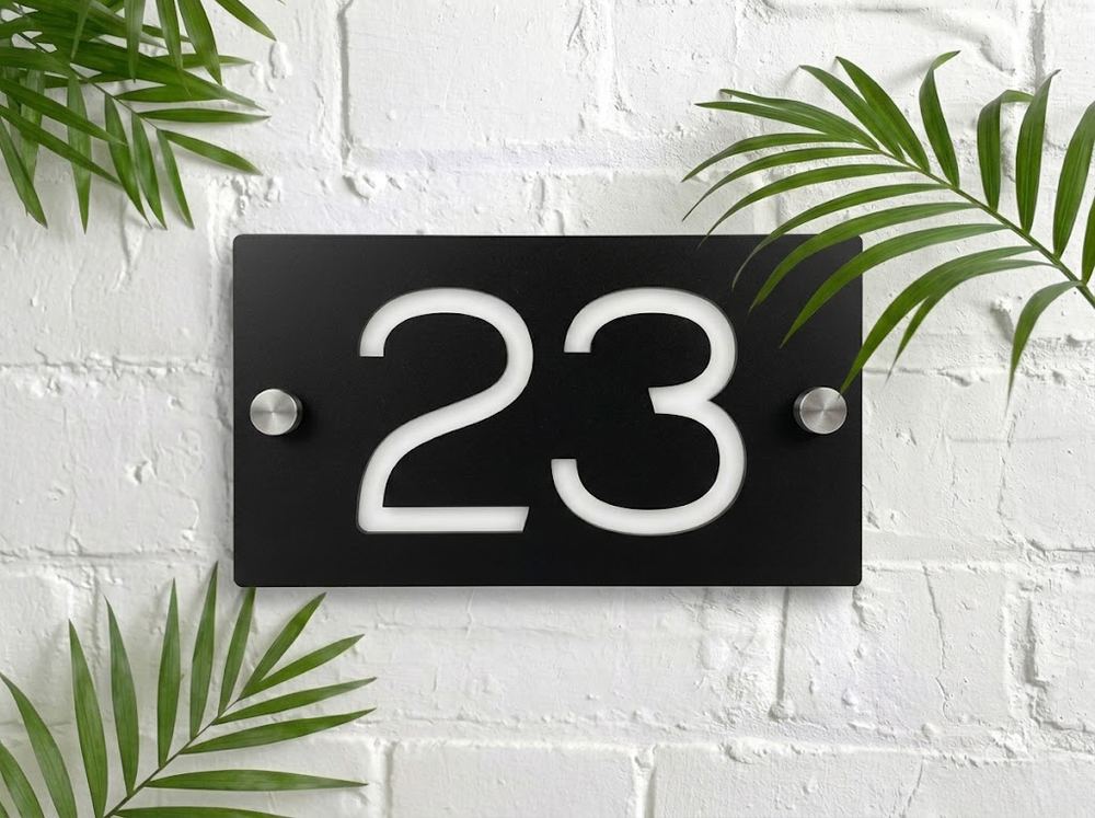 Black acrylic house number sign 23 on a white brick wall